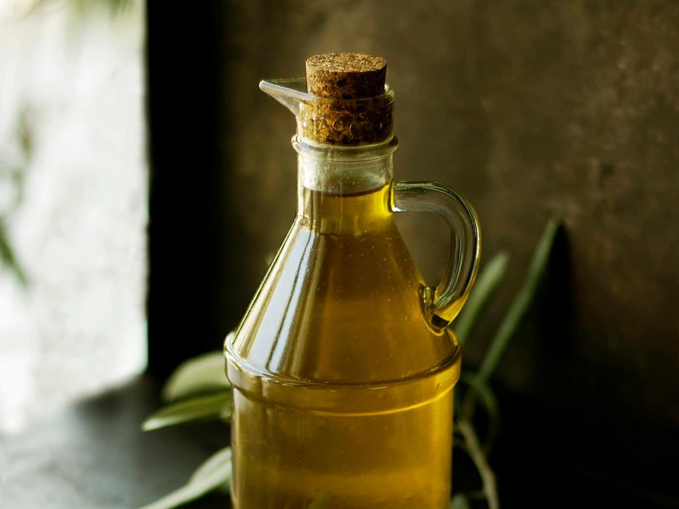 A glass cruet of edible oil on a dark stone surface